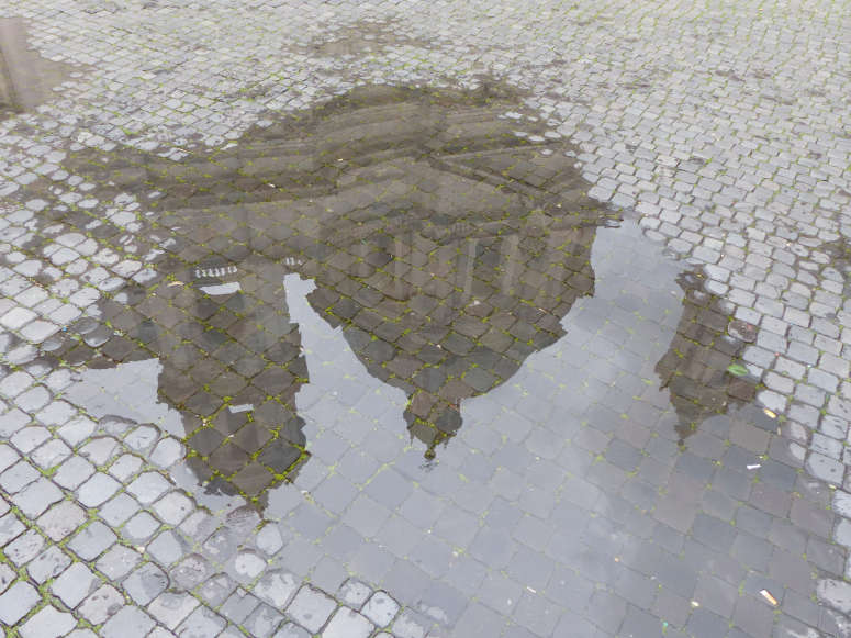 Partial reflection of Piazza Navona's Sant'Agnese in Agone church in a rain puddle