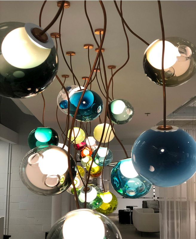 Pendant light fixtures of colorful asymmetric glass shades hung from bendable copper tubing
